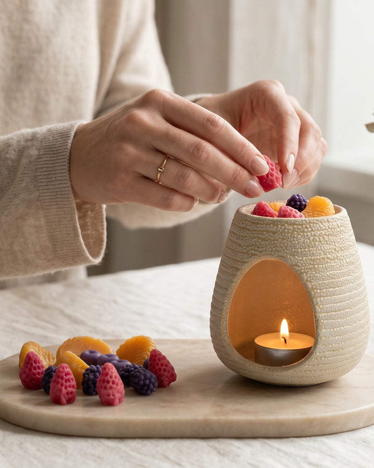 Wax melts Velvet colecția Nectar, căpșuni și felii de portocală lângă arzătorul ceramic crem