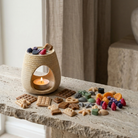 Arzător ceramic crem cu forme de ceară de soia topite, eliberând parfum în cameră